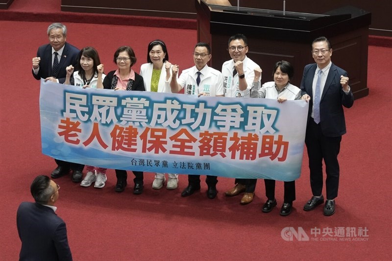 Taiwan People's Party lawmakers hold a placard at the Legislative Yuan on Friday celebrating the passage of a legal amendment requiring the central government to fully subsidize National Health Insurance premiums for certain senior citizens. CNA photo Oct. 16, 2026