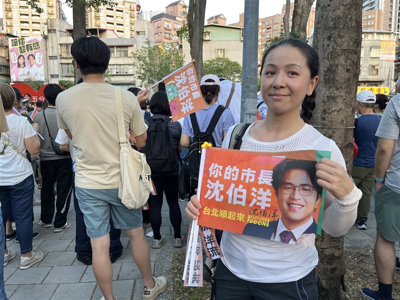 Taipei resident Sharlene Weng holds a campaign flag for Taipei mayoral candidate Puma Shen at Wufenpu Park in the capital's Xinyi District on Sunday. CNA photo Oct. 18, 2026
