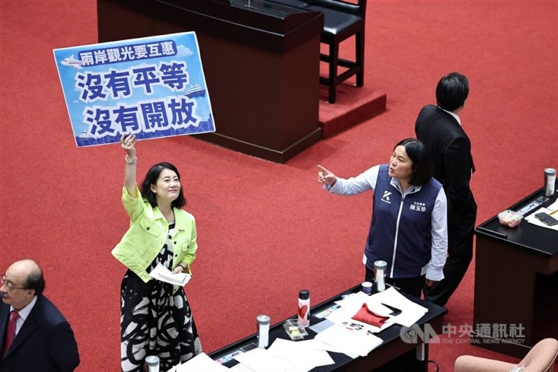 Anggota Parlemen DPP, Wu Szu-yao, mengangkat sebuah plakat yang menekankan bahwa "Taiwan baru akan menerapkan kebijakan pariwisata terbuka jika Tiongkok melakukan hal serupa" di Gedung Yuan Legislatif di Taipei hari Selasa. (Sumber Foto : CNA, 16 Juli 2024)