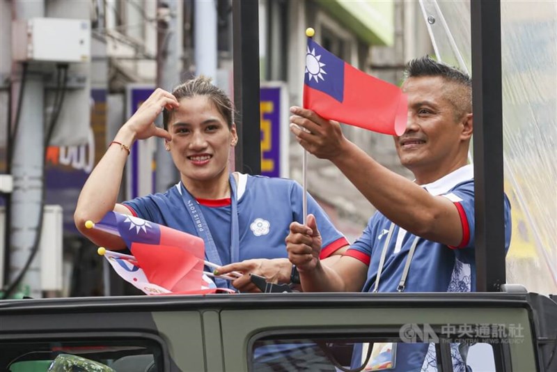 Petinju dan peraih medali perunggu Chen Nien-chin (kiri) membuat pose hati dari sebuah kendaraan di parade, dengan pelatihnya Ko Wen-ming di sampingnya pada hari Jumat. (Sumber Foto : CNA, 16 Agustus 2024)
