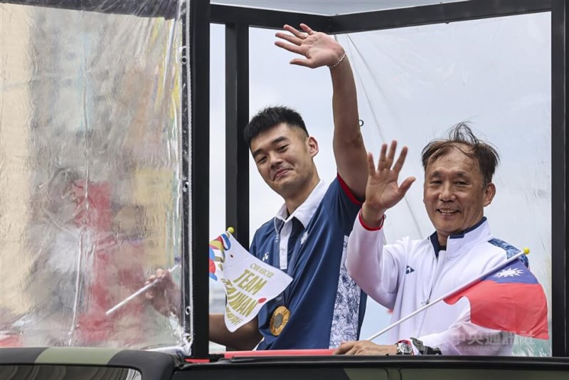 Pemenang medali emas ganda putra bulu tangkis Wang Chi-lin (kiri) melambaikan tangan ke kerumunan dari sebuah kendaraan di parade pada hari Jumat. (Sumber Foto : CNA, 16 Agustus 2024)