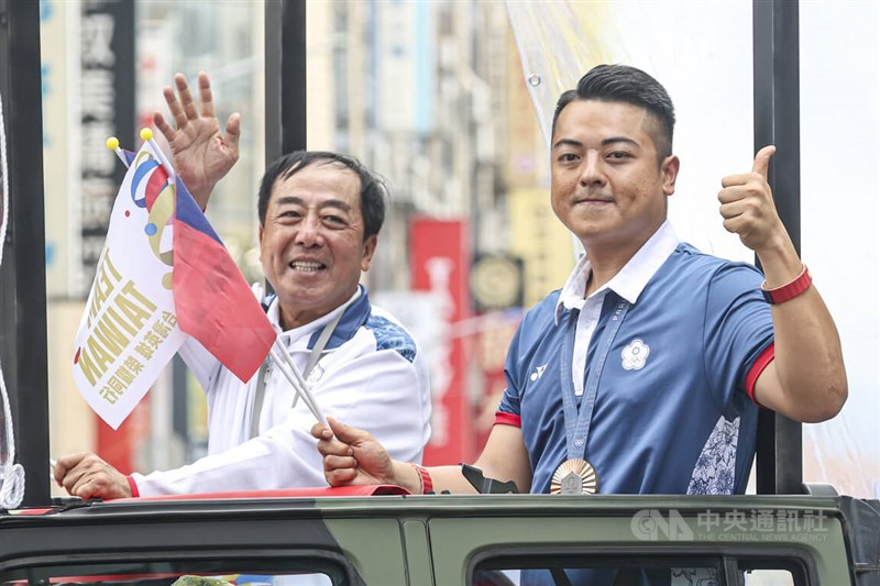 Penembak dan peraih medali perunggu Lee Meng-yuan (kanan) dan ayahnya Hsieh Chih-pei menanggapi kerumunan yang bertepuk tangan di parade pada hari Jumat. (Sumber Foto : CNA, 16 Agustus 2024)