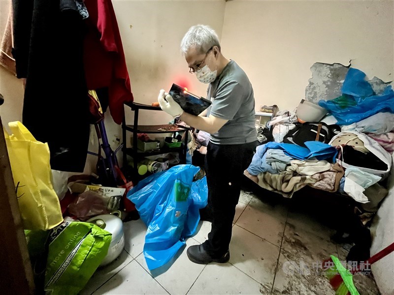 Chen memeriksa lebih dekat suatu barang saat merapikan rumah seorang wanita lanjut usia, yang mengalami masalah penimbunan barang, di Distrik Wanhua, Taipei pada suatu Kamis pagi. Foto CNA 31 Agustus, 2024.