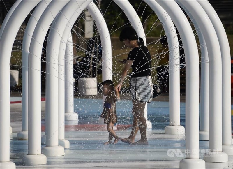 Seorang ibu dan anaknya mendinginkan diri di sebuah taman di Kaohsiung pada Selasa. (Sumber Foto : CNA, 17 September 2024)