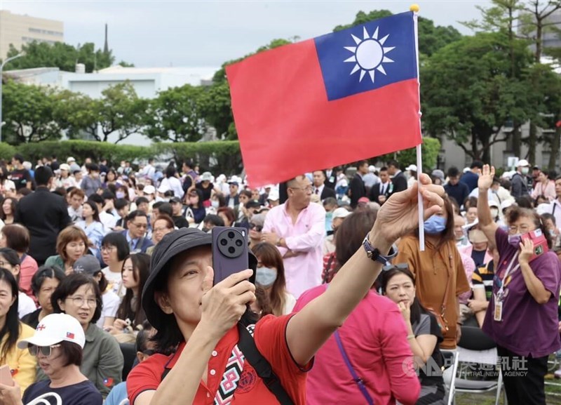 Seorang peserta upacara Hari Nasional 2024 memegang minatur bendera Taiwan. (Sumber Foto : CNA, 10 Oktober 2024)
