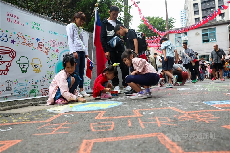 Anak-anak menggambar di tanah Desa Saudara Militer Angkatan Udara Sanchong No. 1, di mana upacara pengibaran bendera New Taipei diadakan Kamis pagi untuk Hari Nasional. (Sumber Foto : CNA, 10 Oktober 2024)