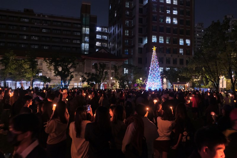 Peserta upacara penyalaan lilin Wenzao Ursuline University of Languages hari Senin mengangkat lilin mereka, di dekat pohon Natal 12 meter. (Sumber Foto : WZU, 3 Desember 2024)
