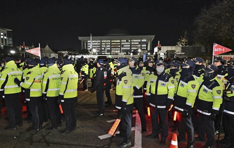 Petugas polisi berjaga di luar Majelis Nasional Korea Selatan pada Rabu dini hari, beberapa jam setelah Presiden Yoon Suk Yeol memberlakukan darurat militer di negara tersebut. (Sumber Foto : Kyodo News, 4 Desember 2024)