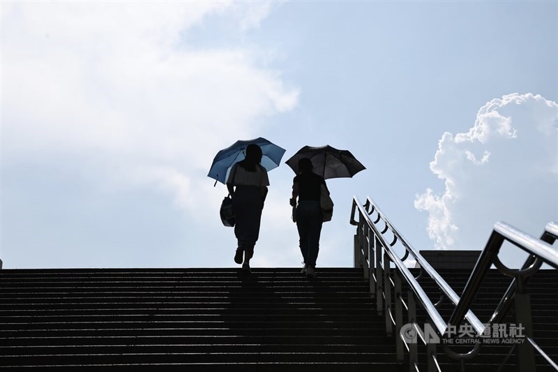 Pejalan kaki berjalan di sepanjang jalan-jalan Taipei dengan payung yang melindungi mereka dari matahari dalam foto arsip CNA ini yang diambil pada Agustus 2024.