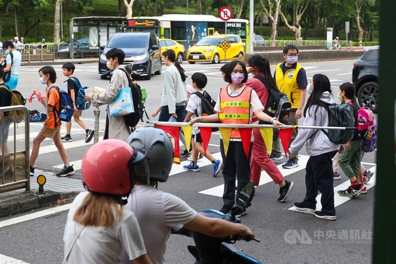 Seorang staf sekolah mengatur lalu lintas untuk memastikan keselamatan siswa sekolah dasar di Taipei. (Sumber Foto : Dokumentasi CNA)