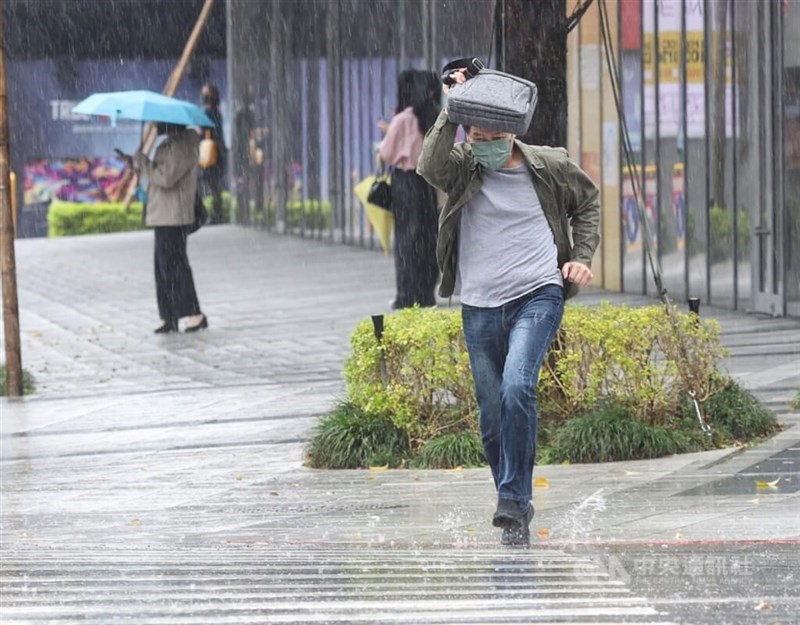 Seorang pria melindungi kepalanya dari hujan dengan tas bawaan di Taipei. (Sumber Foto : Dokumentasi CNA)