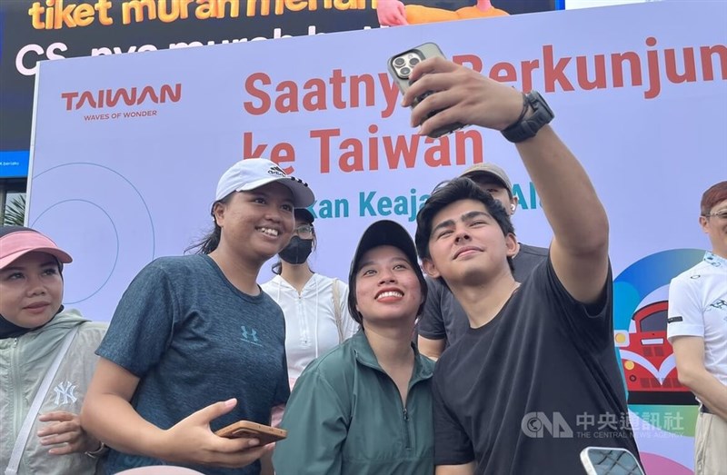 Pemengaruh asal Indonesia, Andrew Kalaweit (depan, kanan) berfoto dengan pengunjung di stan pariwisata Taiwan di Jakarta hari Minggu. (Sumber Foto : CNA, 13 April 2025)