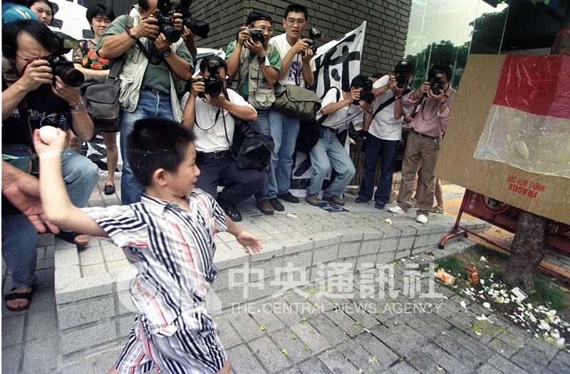 Seorang anak kecil melempar telur ke bendera Indonesia dalam aksi di depan KDEI Taipei, 3 Agustus 1998. (Sumber Foto : Dokumentasi CNA).