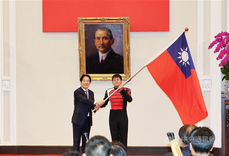Presiden Lai Ching-te (kiri) menyerahkan bendera negara Republik Tiongkok (Taiwan) kepada perwakilan Chien Kuo High School Marching Band yang akan bertanding di Indonesia Agustus mendatang. (Sumber Foto : CNA, 8 Juli 2025)
