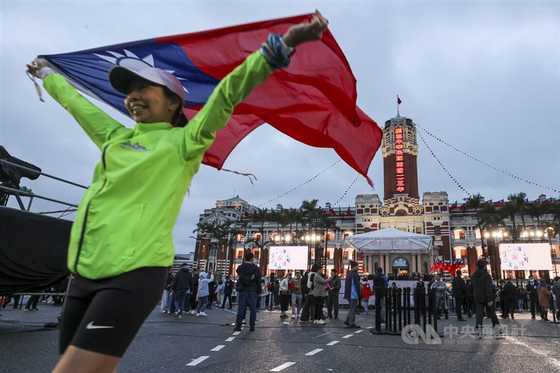 Seorang wanita berlari dengan bendera nasional berkibar tinggi di depan Gedung Kantor Kepresidenan di Taipei pada hari Kamis. Foto CNA 1 Januari 2026