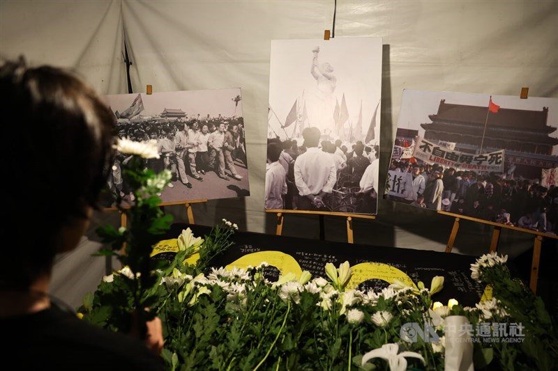 Seseorang meletakkan bunga di sebuah tugu peringatan yang menampilkan gambar-gambar dari protes Lapangan Tiananmen tahun 1989 selama acara doa bersama dengan lilin di Taipei pada hari Kamis. (Sumber Foto : CNA, 4 Juni 2026)
