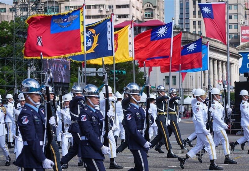 Anggota pasukan kehormatan berparade dengan membawa bendera yang mewakili berbagai cabang angkatan bersenjata. (Sumber Foto : CNA, 10 Oktober 2026)