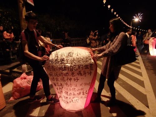 カップルで天灯を飛ばすのは、なんともロマンチック。後ろでは花火も上がっていた。