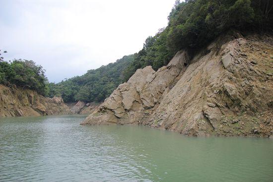 満水時、水位は木が生えているところまで上がる。露出した岩肌には日本統治時代に掘られたという通路の入り口が見える。