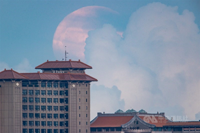 まだ空は明るい午後7時前、台北市内の陽明山で巨大な月が建物後方からゆっくりと顔を出した＝中央社記者鄭清元撮影、2022年7月13日