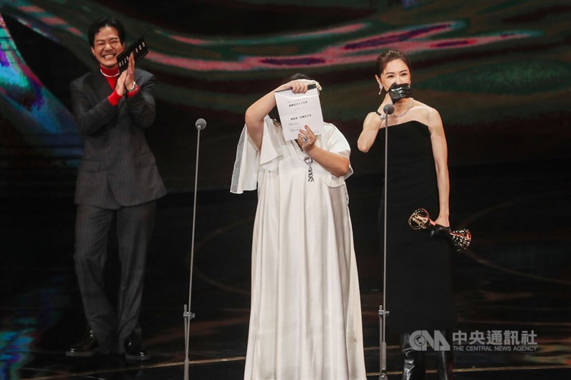 受賞作品を勘違いしていたことに気付き、苦笑を浮かべるシエ・インシュエン（謝盈萱、右）と、受賞者が書かれた紙を客席に見せるプレゼンターのチョン・シンリン（鍾欣凌、中央）＝台北・国父紀念館、 2022年10月22日中央社記者裴禛撮影