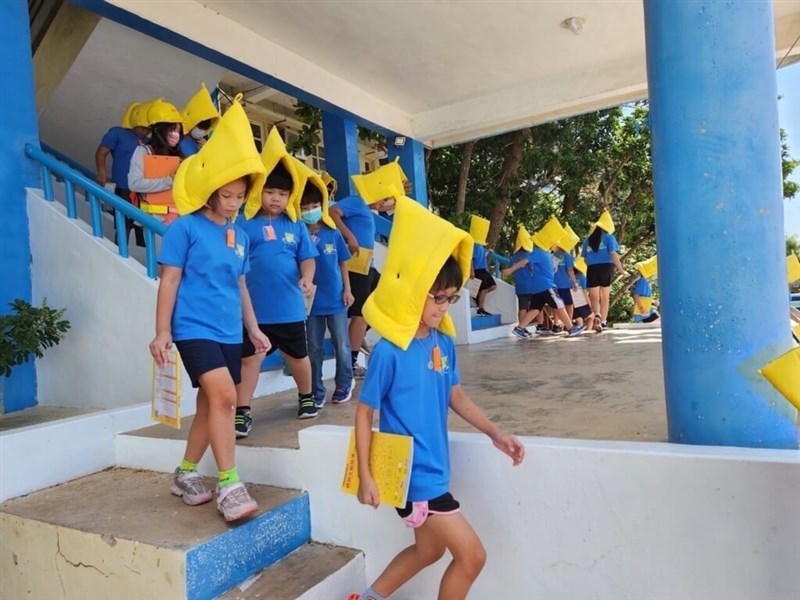 防災頭巾をかぶり階段を使って屋外への避難の訓練をする児童ら=14日、澎湖県龍門小学校(澎湖県政府提供)