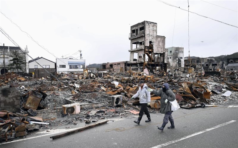 石川県輪島市の被災地を通る人たち＝共同通信社提供