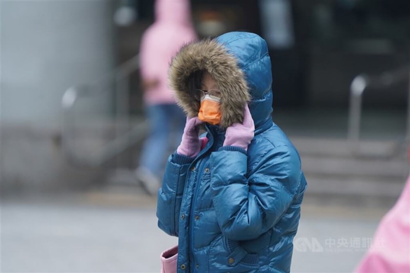 台北市内でダウンジャケットと手袋を着用しフードをかぶって寒さをしのぐ女性＝資料写真