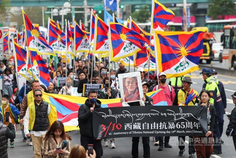 ダライ・ラマ14世の写真やチベットの旗などを掲げて台北市内でデモ行進を行う人々＝10日、裴禛撮影