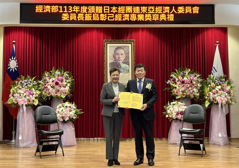 王美花経済部長（左）から「経済専業奨章」を贈られる元三井物産社長の飯島彰己氏（同部提供）