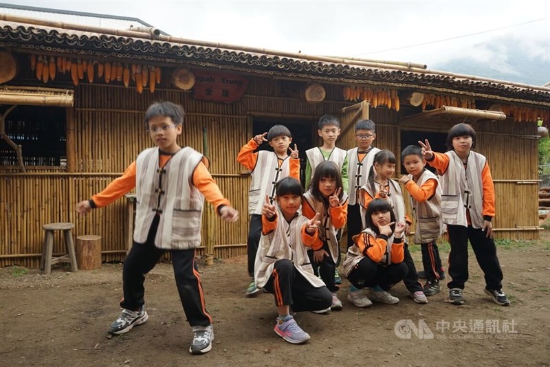 台湾原住民族タロコ族に伝わる伝統的な建築様式で建てられた花蓮県万栄小学校の校舎と児童ら＝3月29日、張祈撮影