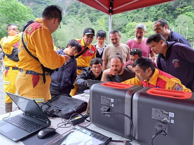 7日、ドローンを使って行方不明者の捜索に加わり、台湾側の救助隊の説明を受けるトルコの救助隊員ら＝消防署（消防庁）提供