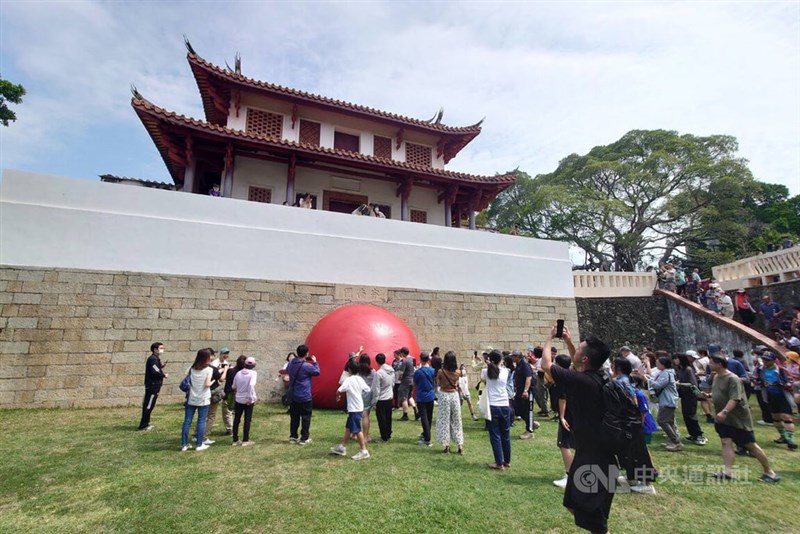 南部・台南市の大南門城で展示されているゴム製の巨大な赤球を撮影しようとしている人たち＝7日、楊思瑞撮影