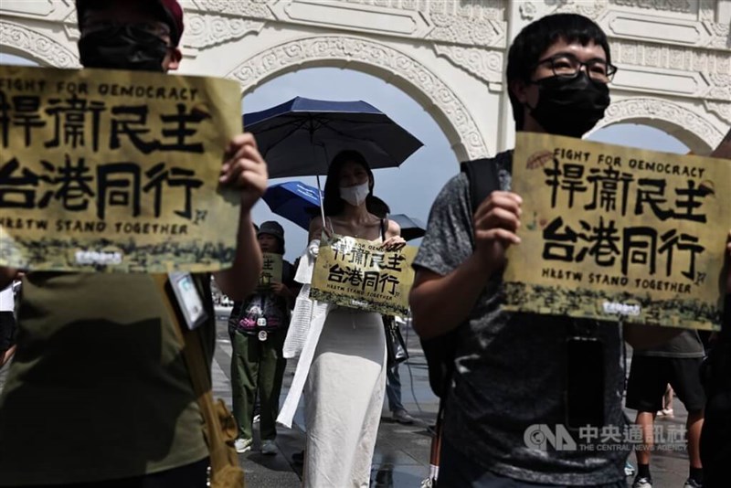 デモ行進のスローガン「民主主義を守れ　台湾と香港は共にある」と書かれた紙を掲げて歩く参加者＝翁睿坤撮影