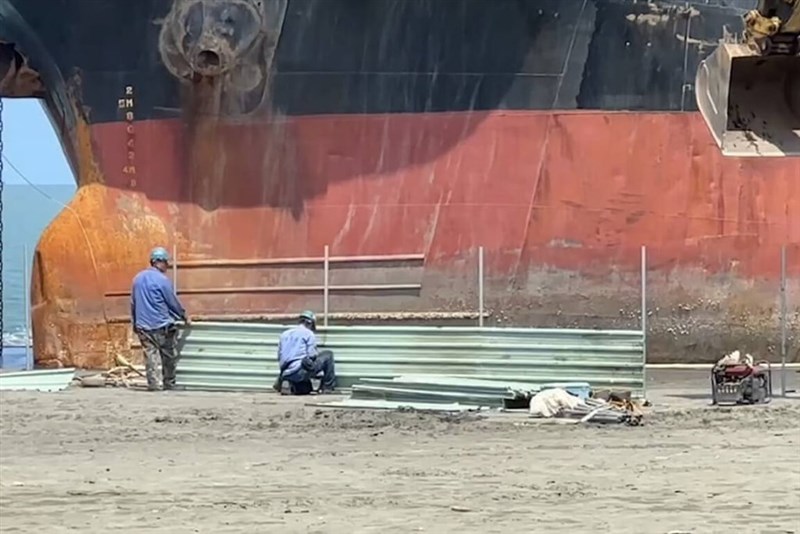 座礁した貨物船の船首近くにフェンスを設置する作業員＝読者提供