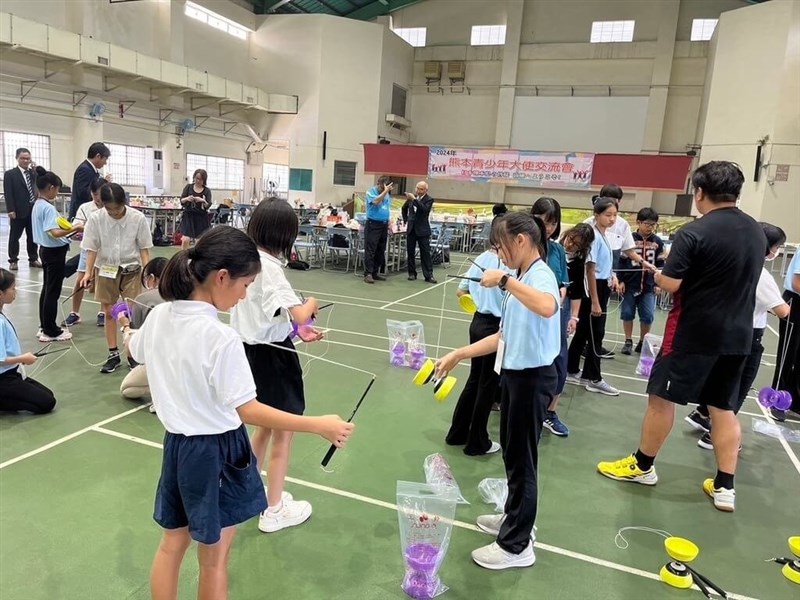 中華圏の伝統的なこま遊び「扯鈴」を楽しむ高雄市と熊本県の児童ら（同市教育局提供）