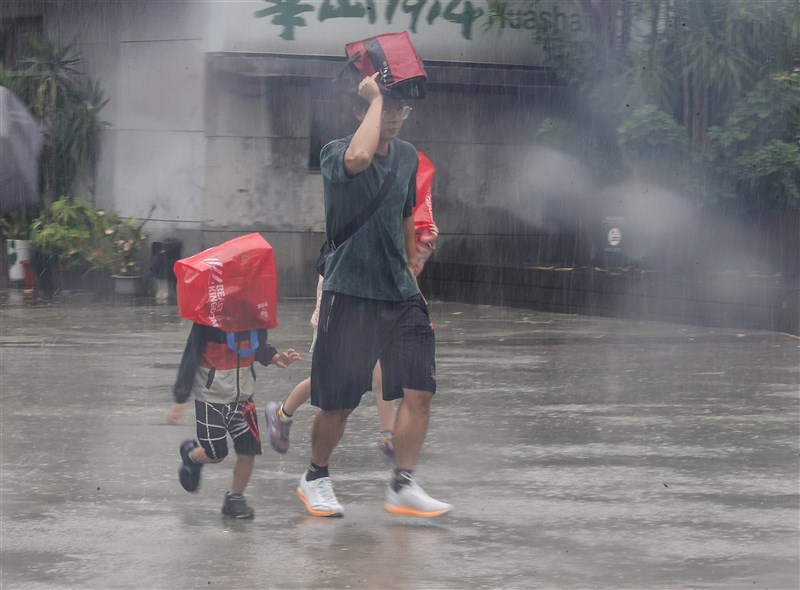 雨の中を歩く家族連れ＝14日、謝佳璋撮影