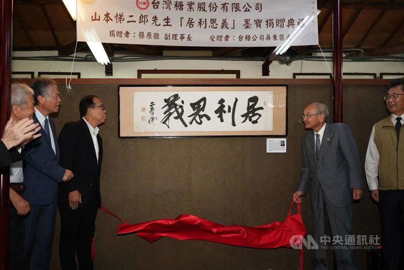 山本悌二郎の揮毫（きごう）した書。右から2人目は山本のひ孫の夫、IMC日本親善大使の篠原徹氏