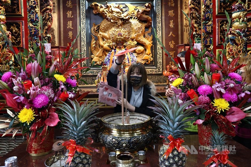 財運向上を願って神に借りる「発財金」を香炉にくぐらせて開運を祈る女性＝台北・洲子福徳廟で2025年1月29日、中央社記者翁睿坤撮影