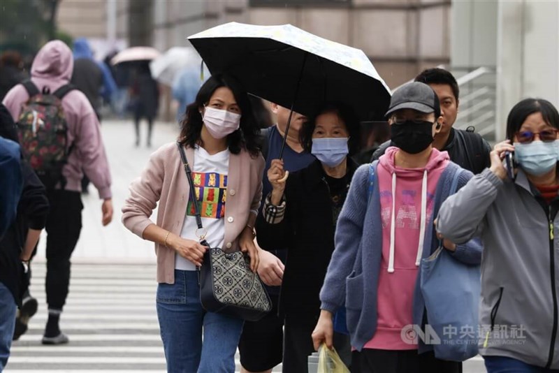 台北市信義区で傘を差したりして道を渡る人たち＝資料写真