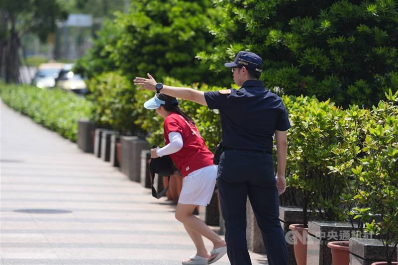 台北市で警察官（右）の指示に従い屋内に避難する歩行者＝2025年7月17日、中央社記者徐肇昌撮影