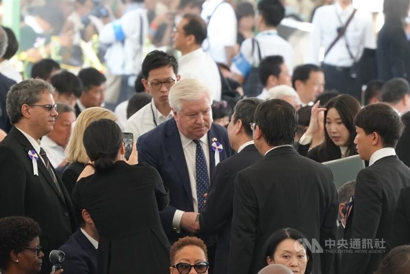 米国のジョージ・グラス駐日大使（白髪の男性）と握手を交わす李逸洋駐日代表＝8月6日、広島市
