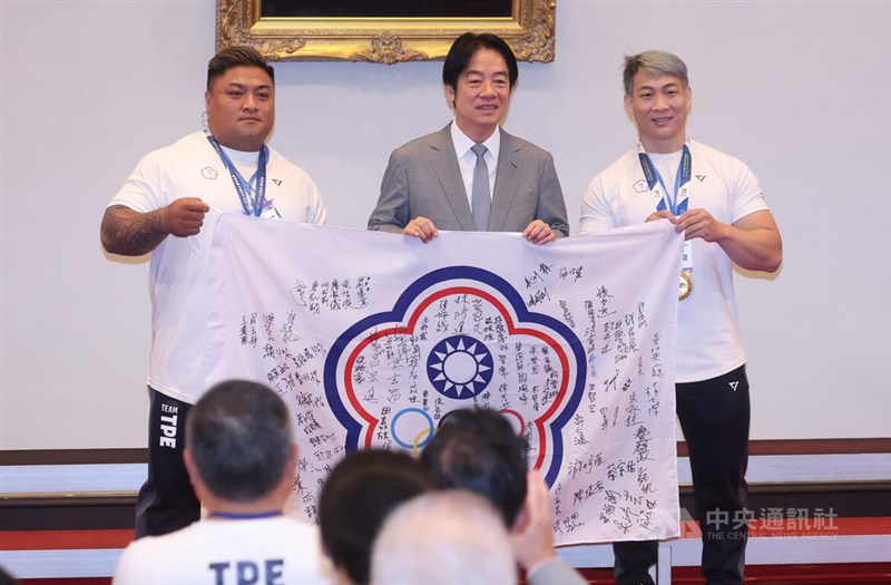 ワールドゲームズ成都大会に出場した台湾代表選手のサイン入り団旗を贈られた頼清徳総統（中央）＝8月21日、台北市