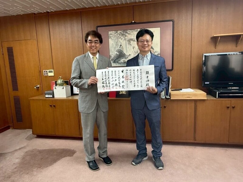 日本棋院の武宮陽光理事長（左）から免状を手渡される顔士浄氏＝8月22日、東京都（東華大学提供）