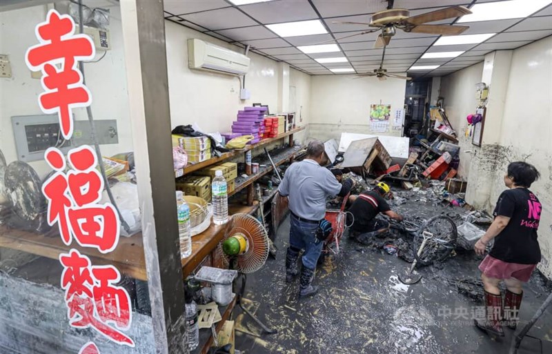 泥まみれになった光復郷の飲食店内で、長靴を履いて清掃作業に追われる人＝2025年9月25日、中央社記者鄭清元撮影