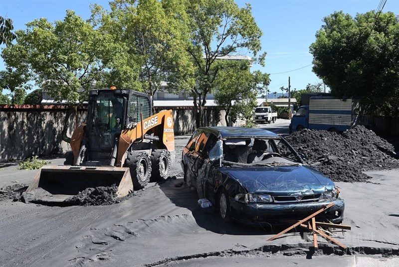 大破した乗用車の脇で道路の泥を除去するブルドーザー＝2025年9月25日、中央社記者郭日暁撮影