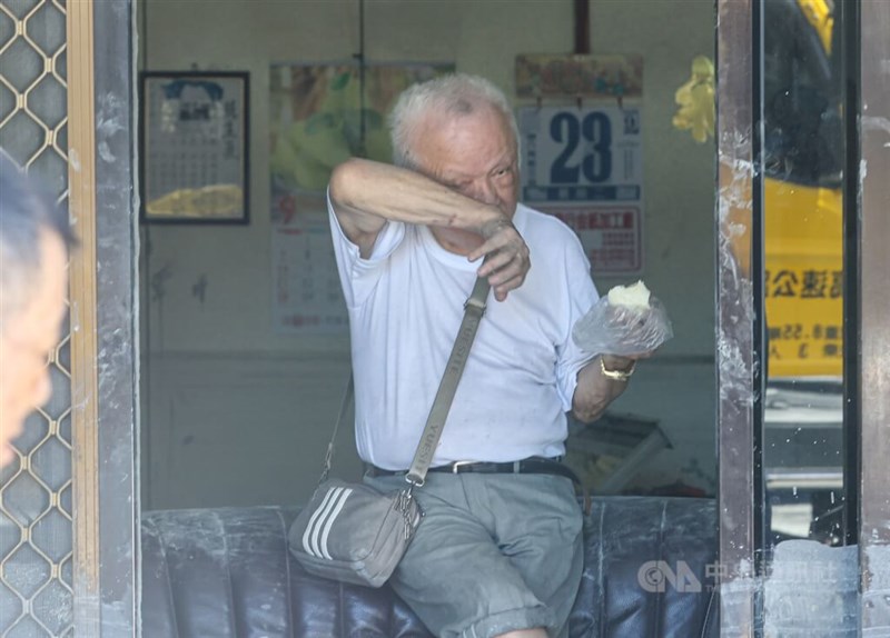 清掃作業の合間に食事を取る男性。手やポシェットには泥が残る＝2025年9月25日、中央社記者鄭清元撮影