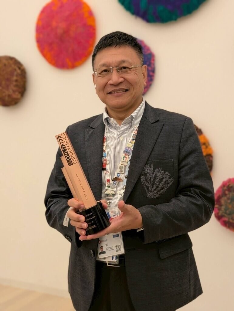 ワールド・エキスポオリンピック展示・ディスプレー部門銅賞のトロフィーを手に持つテックワールド館の邱揮立館長（同館提供）