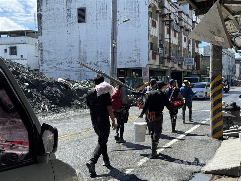 水道管や工具などを持って歩くボランティア＝2025年10月4日、中央社記者張祈撮影