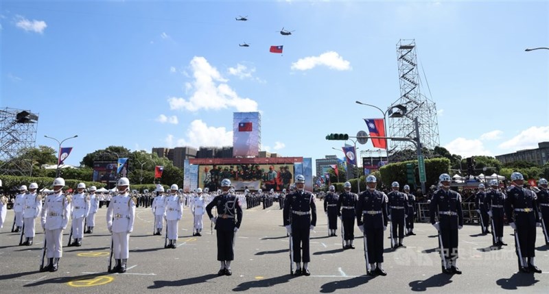 国軍儀仗隊の背後を飛行する巨大な国旗をつるした国軍のヘリコプター＝2025年10月10日、中央社記者張新偉撮影